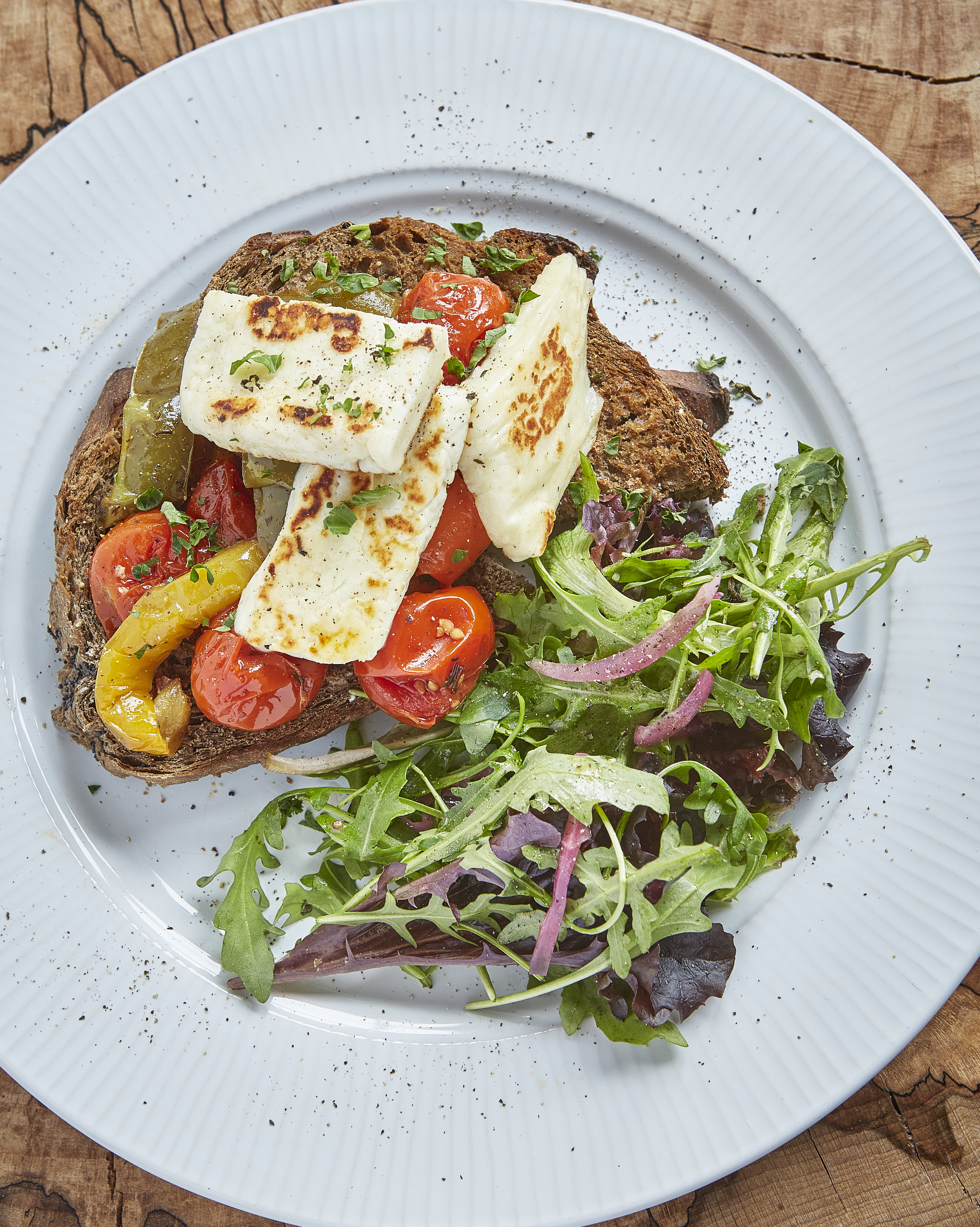 A dish of halloumi on a bed of salad with roast peppers
